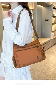 Detalle de bolso bandolera de nailon caramelo con bolsillos con cremallera y correa ancha