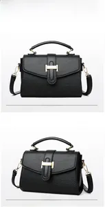 Macro view of black pebbled leather texture with gold buckle detail on crossbody handbag