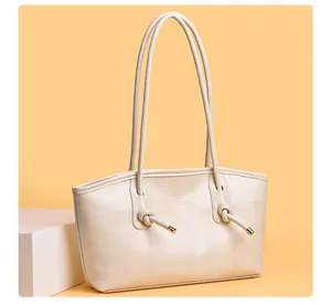 Vue détaillée du sac cabas en cuir blanc crème avec un charme en métal noué et du texte