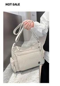 Detalle de bolso bandolera de nailon beige con múltiples bolsillos con cremallera y correa