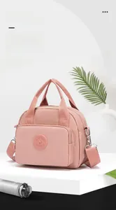 Detail view of the multi-layer compartments and waterproof nylon fabric of pink handbag
