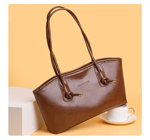 Détail macro du sac cabas marron avec bandoulières nouées et embouts métalliques