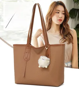 Detailed texture of brown woven tote bag with a cute white plush lamb keychain charm