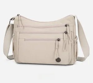Détails de la face avant d'un sac bandoulière beige en nylon imperméable à plusieurs poches