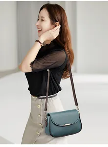 Detail view of stylish green PU leather flap bag with gold clasp on brown shoulder strap