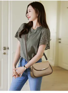 Detail of khaki pebbled leather crossbody bag with gold buckle on a stylish model