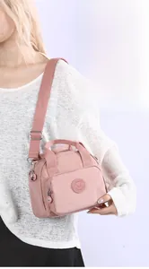 Close-up of pink nylon shoulder bag with adjustable woven strap and front zip pocket