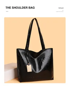 Detail der glänzenden schwarzen Tote-Tasche mit Krokodilprägung und langen Schultergurten