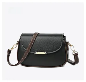 Detail view showing black lychee leather texture and brown trim of the crossbody bag