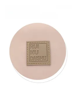 Gros plan du logo RUI MU DAISHU sur tissu sergé rose avec détails de marque en cuir