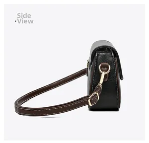 Side view of black pebble leather crossbody bag with brown trim and gold hardware