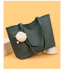 Detail of dark green tote bag with woven texture, leather handle and plush charm accessory