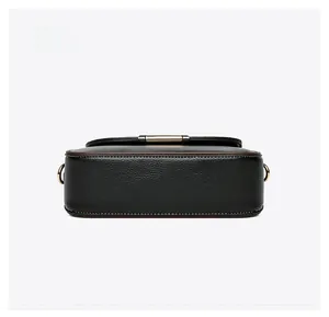 Detailed bottom view of black pebble leather handbag with brown edges and gold metal rings
