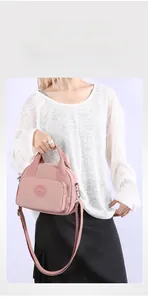 Pink nylon crossbody bag with luggage strap sleeve for secure and easy travel attachment
