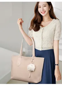 Detail of nude pink woven tote bag with plush pompom on white top model