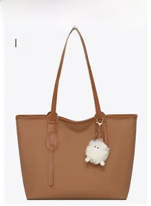 Front view of brown woven texture tote bag with a white plush pompom charm detail