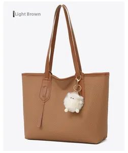 Side view of large brown woven tote bag featuring leather handles and plush charm