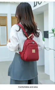 Vue détaillée du mini sac à dos rouge en tissu Oxford avec texture lisse et fermetures éclair