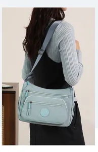 Close-up of a light blue nylon hobo bag with multiple zip pockets and adjustable strap