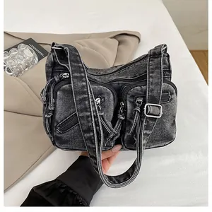 Détail du sac bandoulière en denim délavé avec poches multiples zippées et large bandoulière