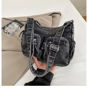 Détail du sac bandoulière en denim noir délavé avec poches multiples et bandoulière réglable