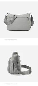 Detail view of a grey nylon crossbody bag showing multiple pockets and adjustable shoulder strap