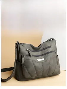 Detail of grey multi-zipper leather crossbody bag with silver hardware and adjustable strap