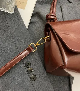 Detailaufnahme der glänzenden braunen Ledertasche mit goldener Hardware und Textur