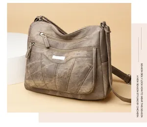 Detailed view of brown vintage leather crossbody bag with triple zipper pockets