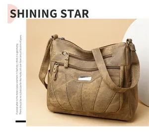 Detail of a brown textured faux leather crossbody bag featuring multiple zipper pockets