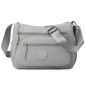 Water-resistant light grey nylon crossbody bag with multi-pocket design and wide strap