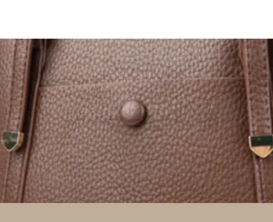 Close-up of brown lychee-textured leather tote bag with gold metal hardware detailing