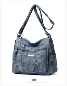Detail of blue denim textured crossbody bag with multi-layer zippers and adjustable strap