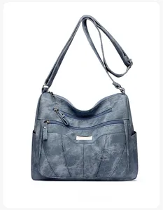 Detailed view of gray-blue soft leather crossbody bag with multiple zipper pockets