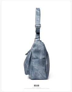 Side view of blue canvas shoulder bag showing multi-layer zippers and metal buckles