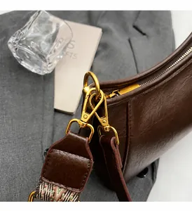 Détail d'un sac vintage en cuir marron avec boucle dorée et bandoulière tissée ethnique