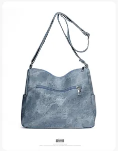 Detail view of the back of a blue denim shoulder bag featuring a smooth zipper pocket