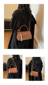 Details der braunen Vintage-Lederhandtasche mit Goldbeschlägen und Perlenanhänger