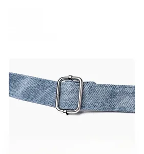 Detail of adjustable silver metal buckle on a blue denim shoulder bag strap