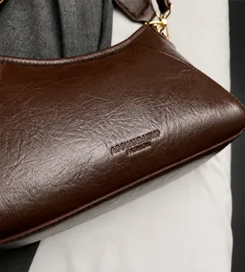 Gros plan du sac en cuir marron avec logo embossé et boucle en métal doré détaillé