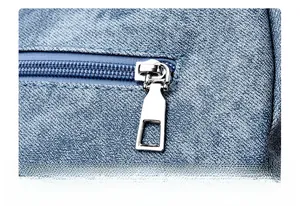 Detail of premium silver metal zipper puller on a blue denim shoulder bag
