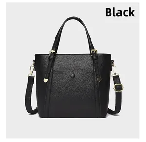 Detail of black lychee grain leather tote with gold hardware and adjustable strap