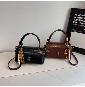 Nahaufnahme von Vintage-Ledertaschen mit Holzperlenanhängern und Goldbeschlägen