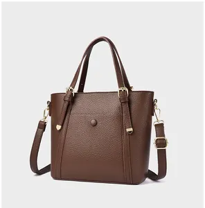Close-up of textured coffee brown leather tote with golden buckles and detachable strap