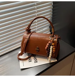 Detail einer braunen Vintage-Handtasche mit Perlen-Quaste und Metall-Drehverschluss