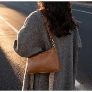 Sac sous le bras en cuir marron sur l'épaule d'un mannequin sous la lumière naturelle