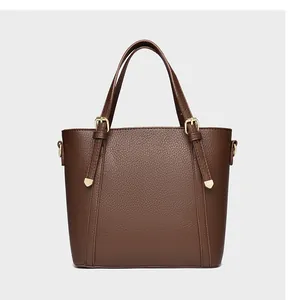 Detail of dark brown pebble leather tote bag with adjustable handles and gold hardware