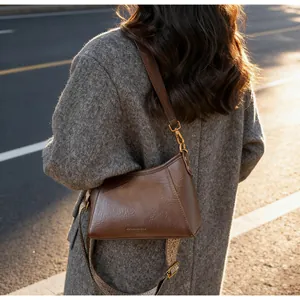Détail du sac bandoulière en cuir marron vintage avec sangle jacquard et dorures