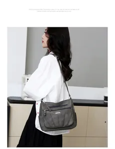 Side view of woman wearing a grey pebble leather crossbody bag with multiple zip pockets