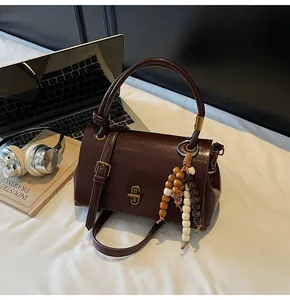 Detailansicht der braunen Vintage-Ledertasche mit dekorativem Perlenanhänger